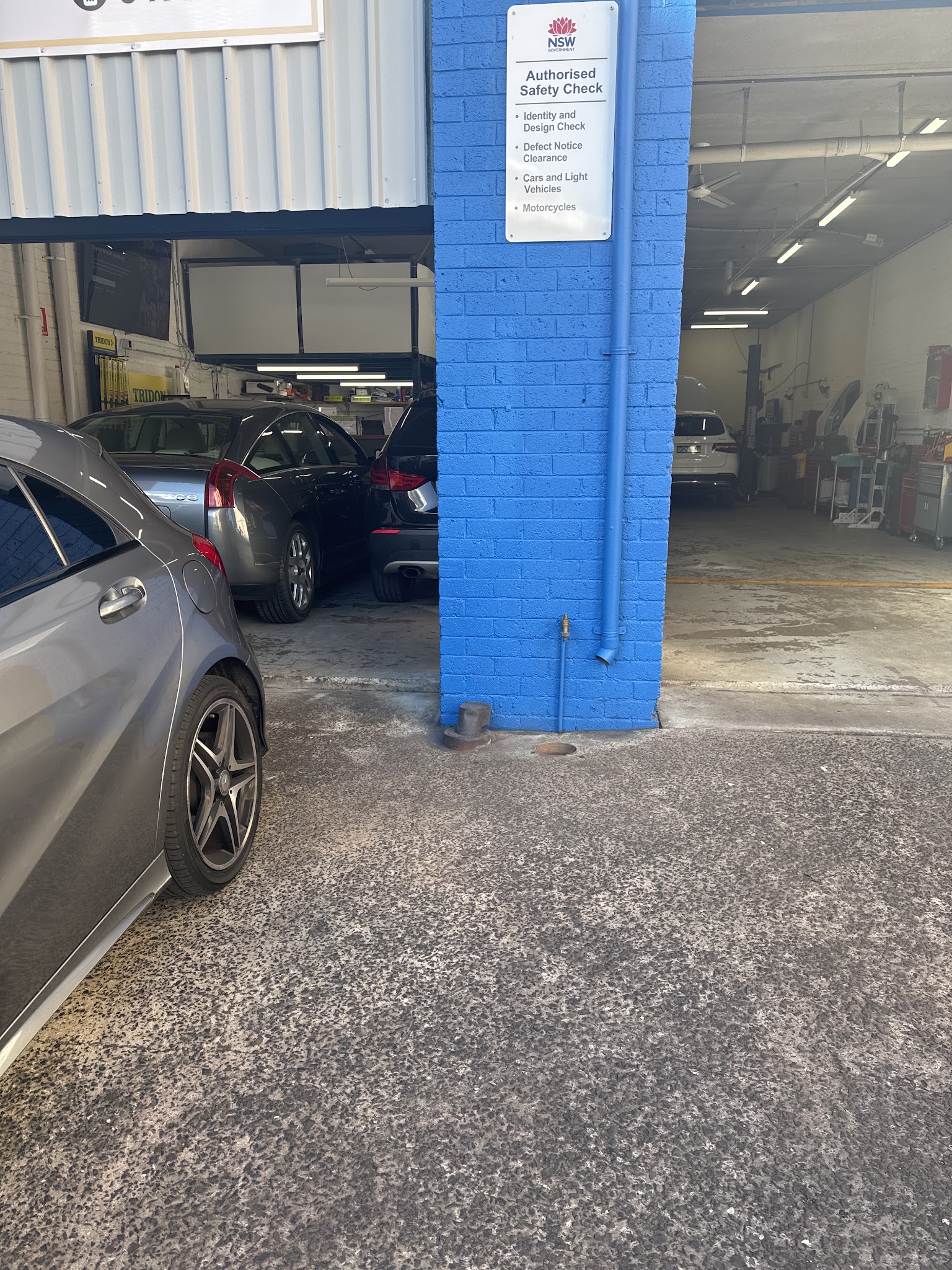 Inside the Precision Mechanics workshop — hoist, tool cabinets and the NSW Authorised Safety Check sign